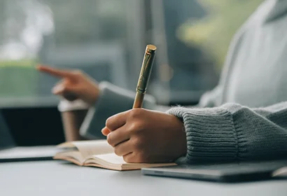Woman writing in a notebook with a pen